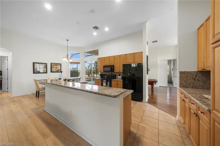 Kitchen with tasteful backsplash, black appliances, arched walkways, light stone countertops, and a high ceiling
