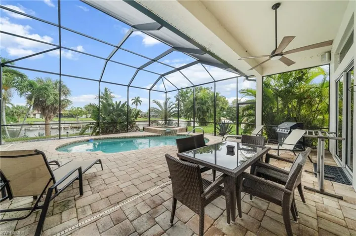 Combined pool / hot tub featuring a sunroom, a patio area, a lanai, outdoor dining area, and area for grilling