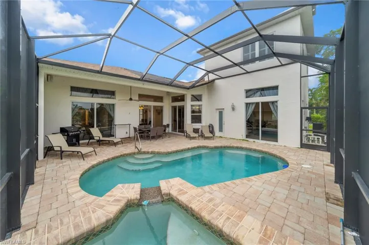 Rear view of house featuring a sunroom, a patio, outdoor dining space, stucco siding, and a pool with connected hot tub