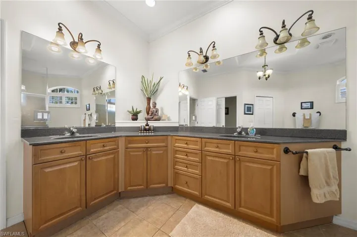 Bathroom with double vanity, crown molding, and light tile patterned floors