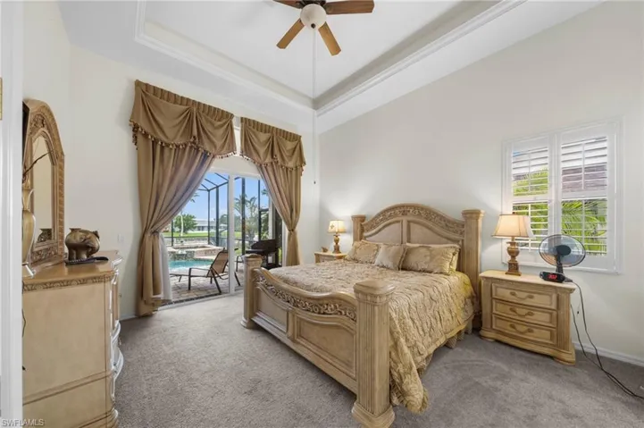 Bedroom featuring access to outside, a ceiling fan, light carpet, and a raised ceiling