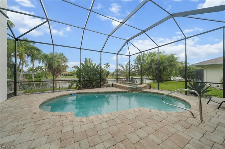 Integrated pool / spa featuring a sunroom, a lanai, a patio area, and a water view
