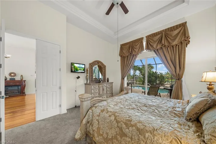 Bedroom with access to exterior, crown molding, carpet floors, ceiling fan, and a tray ceiling