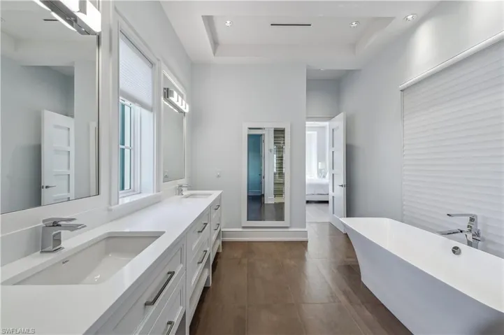 Bathroom featuring a tray ceiling, a bathtub, and vanity