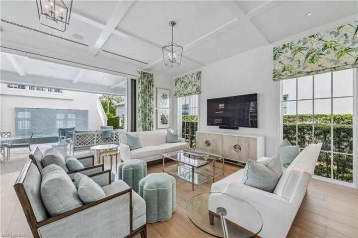 Living room featuring a chandelier, beam ceiling, light hardwood / wood-style floors, and coffered ceiling