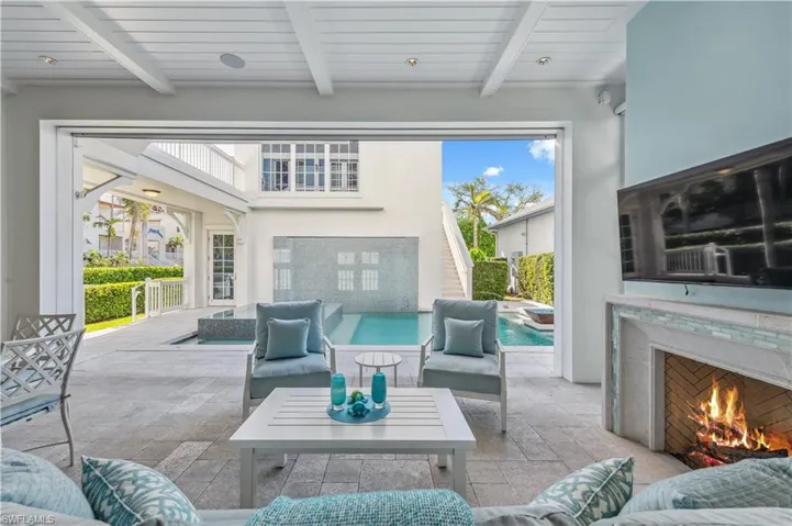 Sunroom / solarium with beamed ceiling, wood ceiling, and exterior fireplace