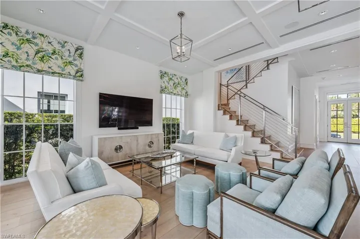 Living room with a chandelier, french doors, light hardwood / wood-style floors, and coffered ceiling