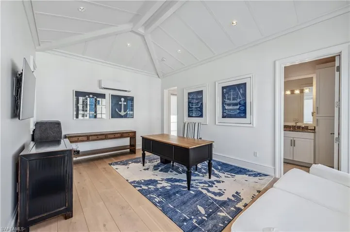 Office space with lofted ceiling with beams, an AC wall unit, sink, light hardwood / wood-style floors, and a healthy amount of sunlight