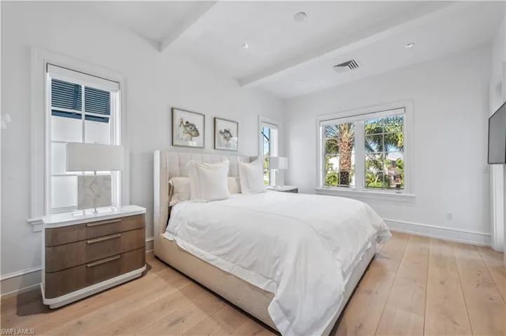 Bedroom with beam ceiling and light hardwood / wood-style floors