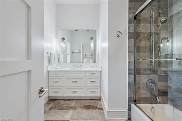 Bathroom with vanity and combined bath / shower with glass door