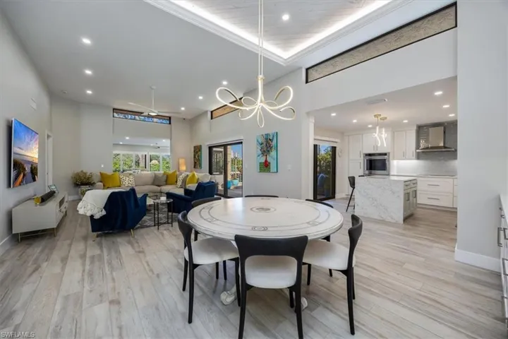 Dining area featuring a notable chandelier, a towering ceiling, plenty of natural light, and light wood-type flooring