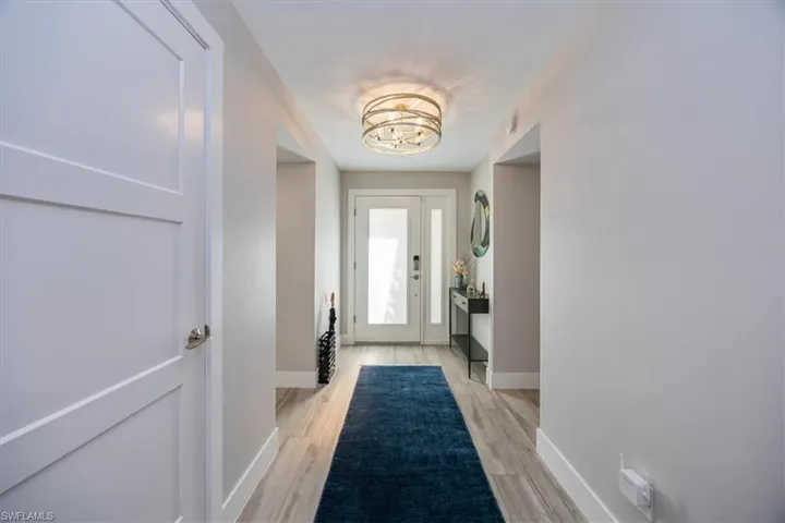 Doorway to outside featuring a chandelier and light wood-type flooring