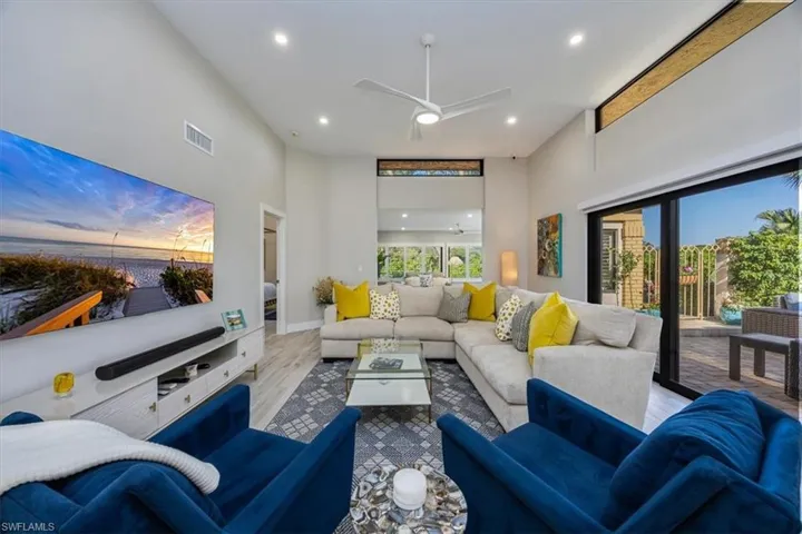 Living room featuring ceiling fan, light hardwood / wood-style floors, and a high ceiling