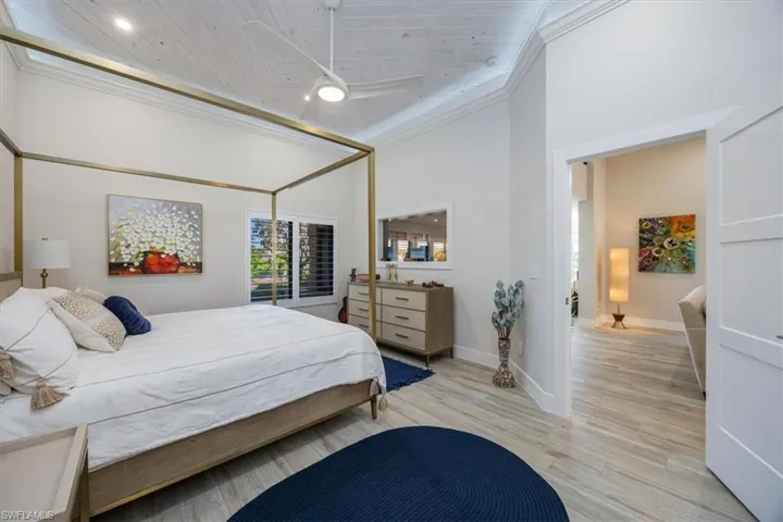 Bedroom with ornamental molding, a towering ceiling, and light hardwood / wood-style floors