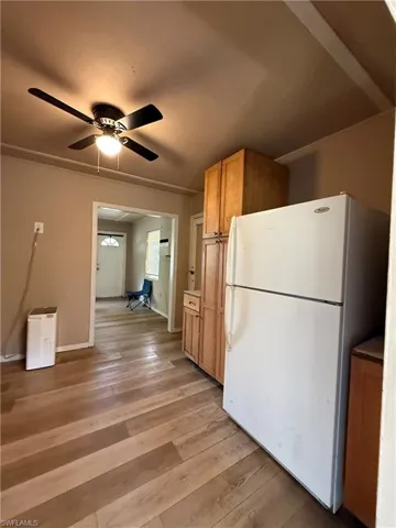 Kitchen featuring freestanding refrigerator, light wood-style floors, ceiling fan, light countertops, and light wood finish cabinets
