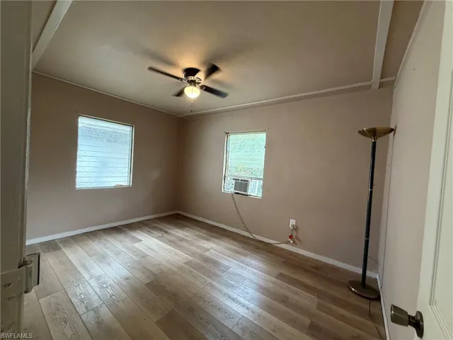 Empty room with light wood finished floors, a ceiling fan, and cooling unit
