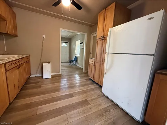 Kitchen featuring freestanding refrigerator, wood finish cabinets, light wood-style floors, ceiling fan, and light countertops