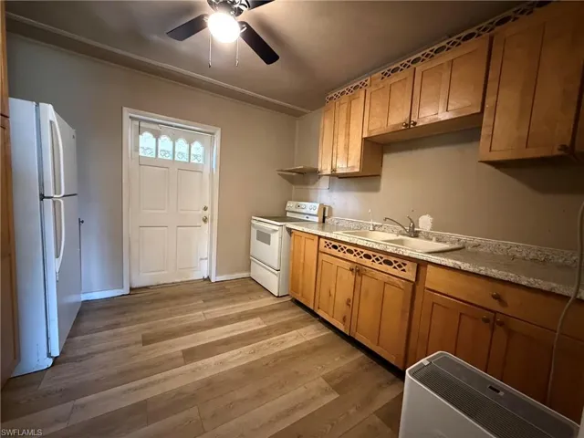 Kitchen with ceiling fan, white appliances, light countertops, wood finish cabinets, and light wood-style floors