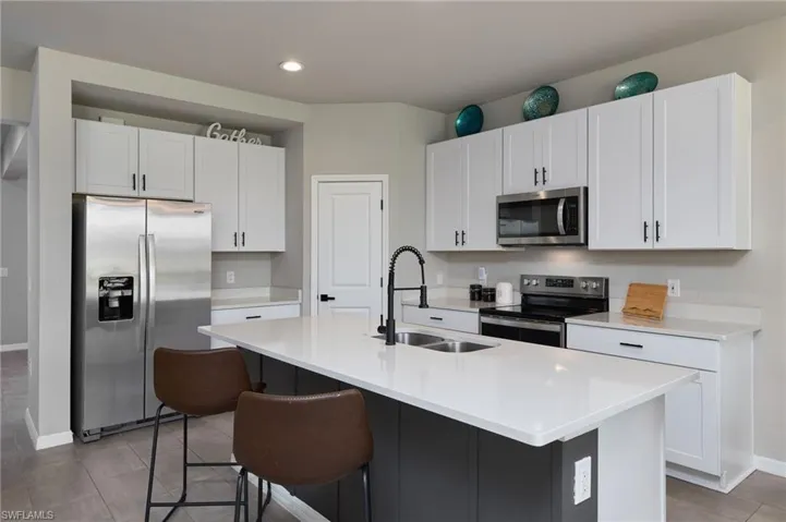 Kitchen with appliances with stainless steel finishes, a center island with sink, white cabinetry, and sink