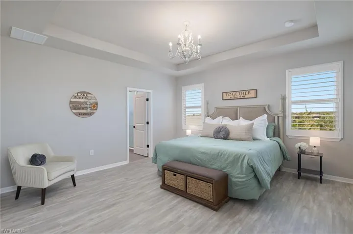 MASTER Bedroom with an inviting chandelier, a tray ceiling, and wood-type flooring