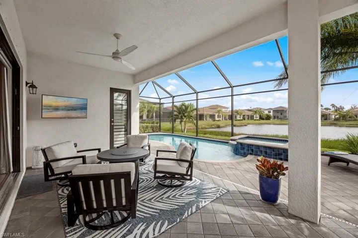 View of patio featuring a swimming pool with hot tub, a water view, a lanai, and ceiling fan