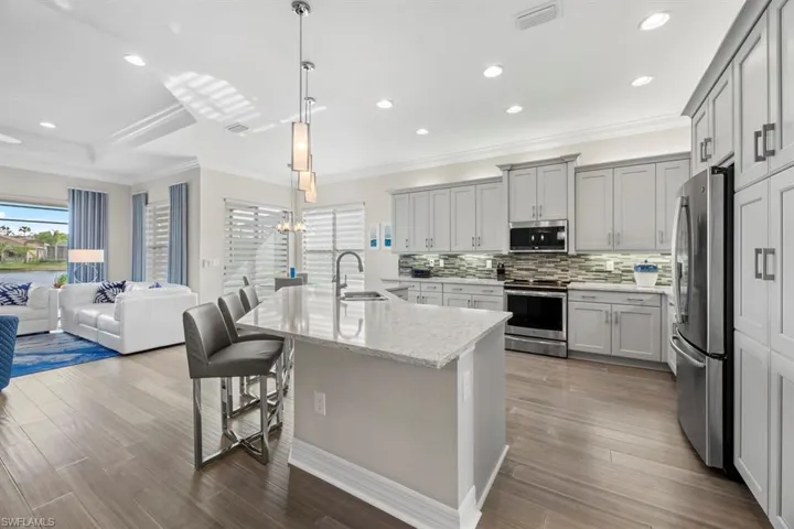 Kitchen with stainless steel appliances, a kitchen breakfast bar, pendant lighting, and hardwood / wood-style floors
