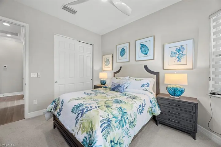 Bedroom with light colored carpet, ceiling fan, and a closet
