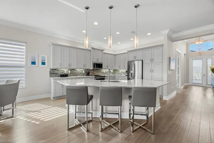 Kitchen with sink, decorative light fixtures, a kitchen island with sink, and stainless steel appliances