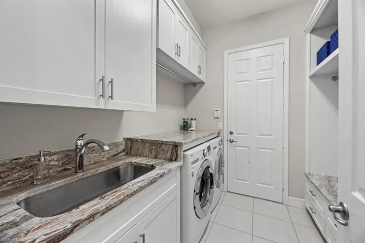 Laundry room featuring cabinets, washer and clothes dryer, sink, and light tile patterned floors