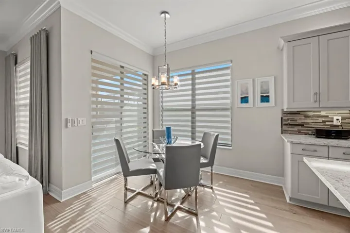 Dining space featuring ornamental molding, light wood-type flooring, and a notable chandelier