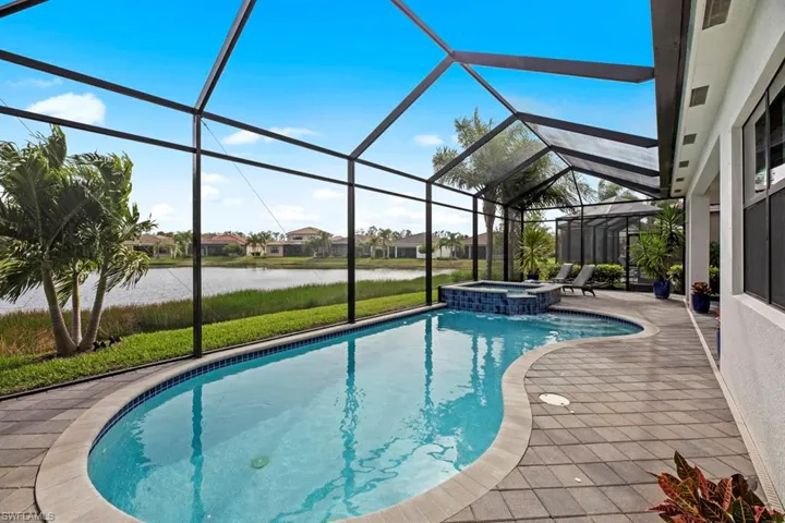 View of pool featuring a water view, glass enclosure, and a patio area