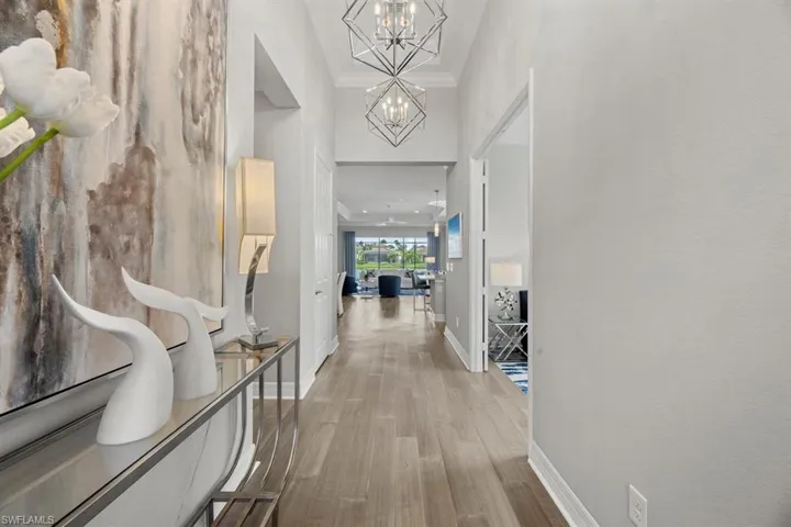 Hall featuring a high ceiling, a chandelier, hardwood / wood-style floors, and ornamental molding