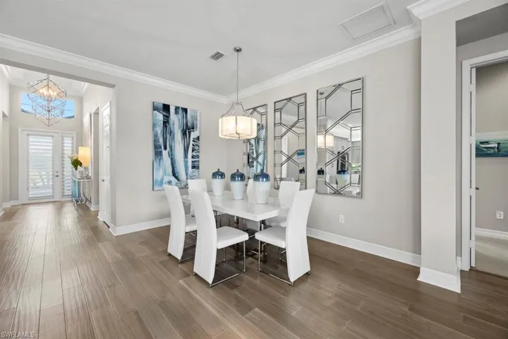 Dining room featuring dark hardwood / wood-style floors, crown molding, and an inviting chandelier