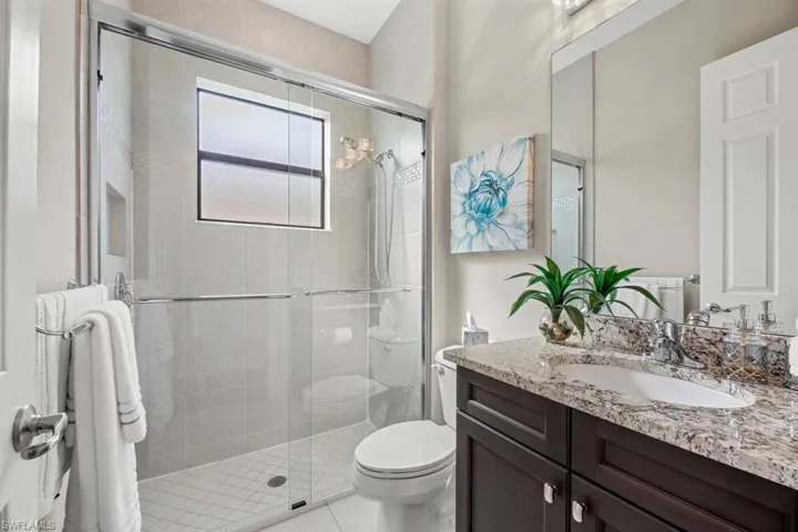 Bathroom with tile patterned flooring, an enclosed shower, vanity, and toilet