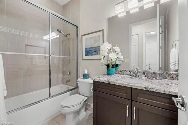 Full bathroom with toilet, shower / bath combination with glass door, tile patterned floors, and vanity