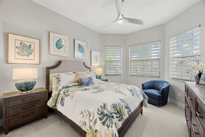 Bedroom featuring light carpet, multiple windows, and ceiling fan