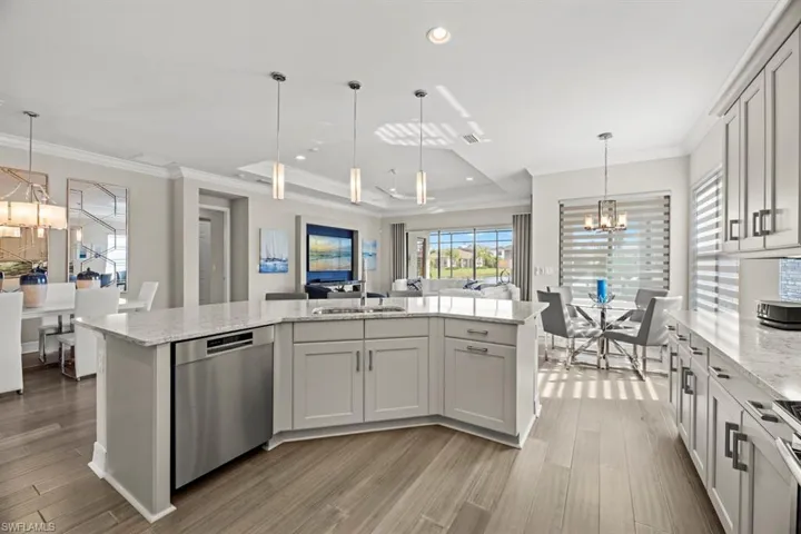Kitchen with dishwasher, a center island with sink, sink, and decorative light fixtures