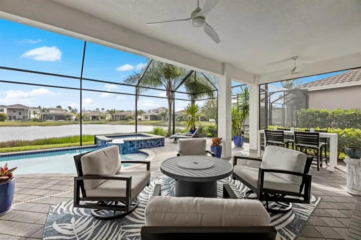 View of patio / terrace with a swimming pool with hot tub, a water view, a lanai, and ceiling fan