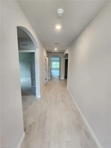 Corridor with arched walkways and light wood-type flooring