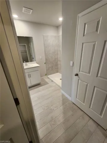 Full bath featuring a stall shower, vanity, wood finish floors, and recessed lighting