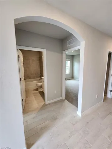 Corridor featuring arched walkways and baseboards