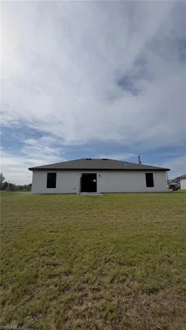 Rear view of property featuring a yard and stucco siding