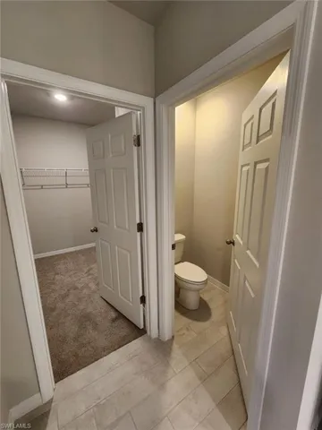 Bathroom with a walk in closet and light carpet