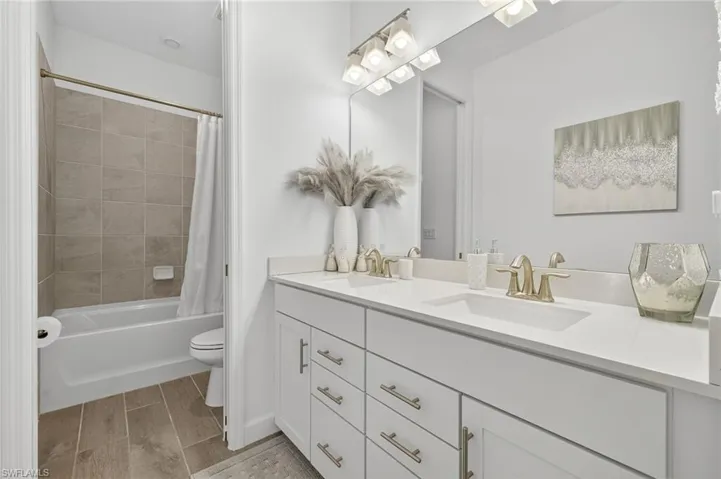 Full bathroom with double vanity and shower / tub combo