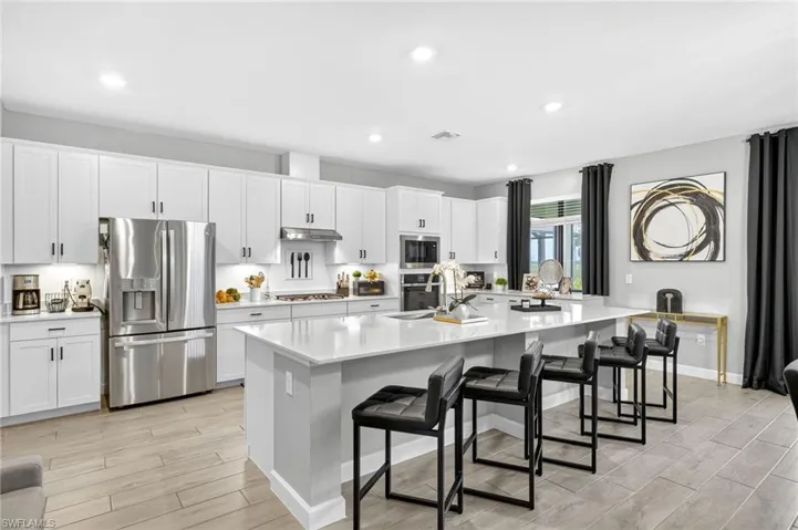 Kitchen with appliances with stainless steel finishes, light wood-style flooring, light countertops, white cabinets, and recessed lighting