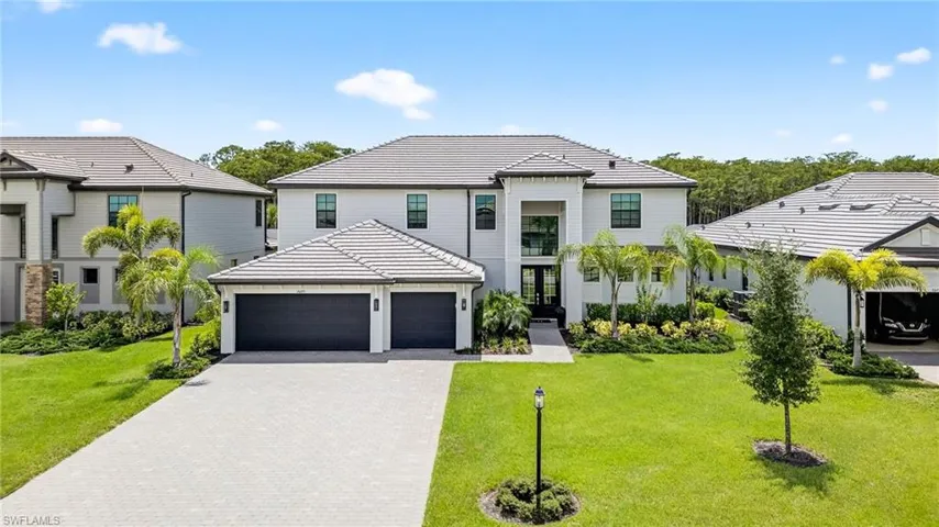 View of front of property featuring a tile roof, a garage, decorative driveway, and a front yard