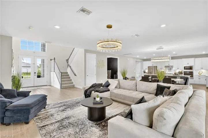 Living room featuring a chandelier, french doors, stairs, recessed lighting, and light wood-style floors