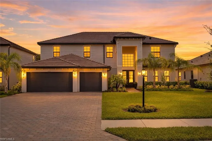 View of front facade with a tile roof, decorative driveway, a lawn, and an attached garage