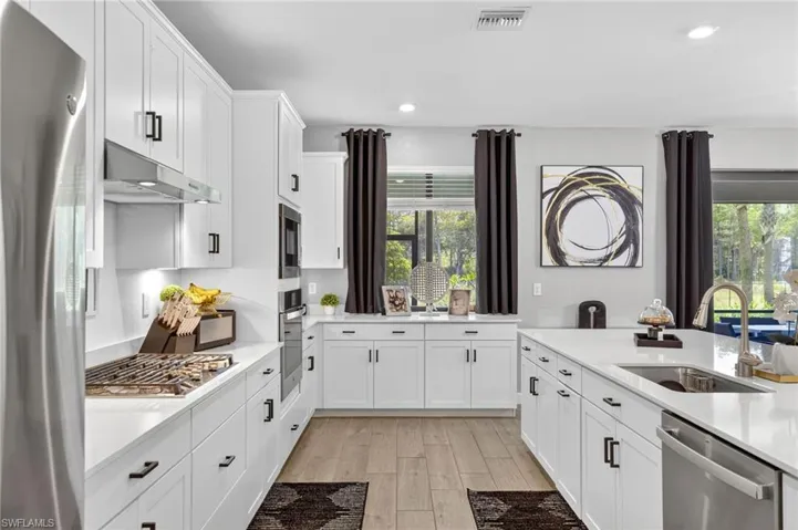 Kitchen with appliances with stainless steel finishes, light wood-type flooring, light countertops, plenty of natural light, and recessed lighting