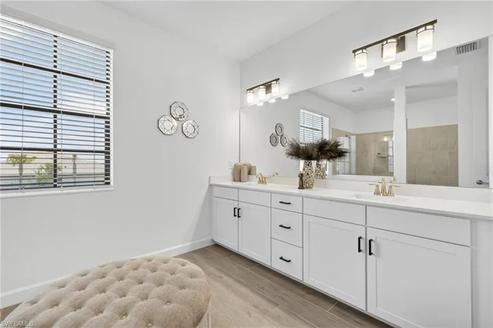 Bathroom featuring double vanity, a walk in shower, and wood finished floors